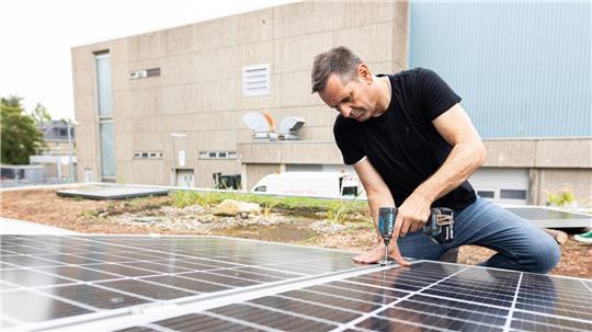 Olaf Lies, damals noch als Wirtschaftsminister, montiert ein Solarmodul auf ein Dach. (Archivbild)
