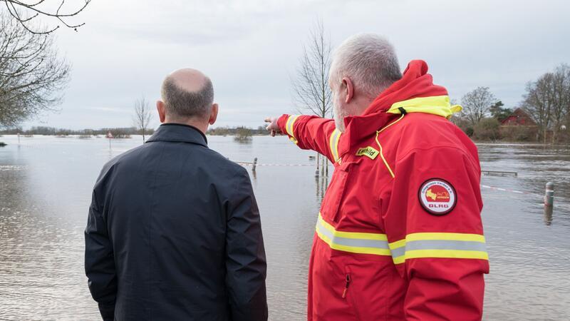 Scholz dankt Helfern - Lage weiter angespannt Olaf Scholz (l) steht mit einem Helfer der DLRG an einem überfluteten Gebiet in Verden/Aller.