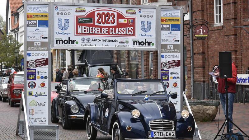 Oldtimer fahren während der Autoschau "Buxtehude brummt" im Jahr 2023 am Rathaus vorbei.