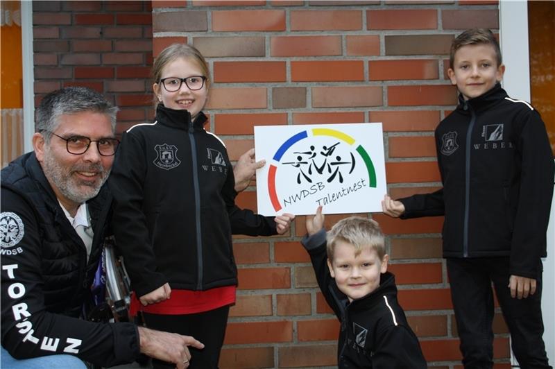 Ole Peters, Bennet Baruth und Lisa-Marie Haack (von rechts) nehmen das Talentnest-Schild von Torsten Meinking entgegen. Meinking ist beim Verband für die Jugendarbeit zuständig.