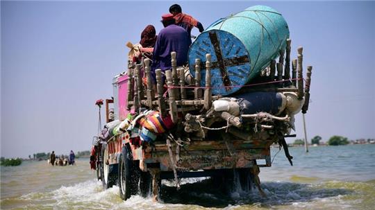 Opfer von Überschwemmungen durch Monsunregen tragen Habseligkeiten aus ihrem überfluteten Haus in der pakistanischen Provinz Sindh (Archivbild). Allein Überschwemmungen könnten Schätzungen zufolge bis 2050 für 8,5 Millionen Tote sorgen.