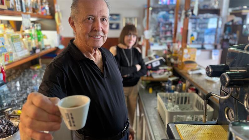 Orlando Paldino zeigt stolz eine Tasse Espresso für 70 Cent. Im Hintergrund steht seine Frau Rosina Furiati.