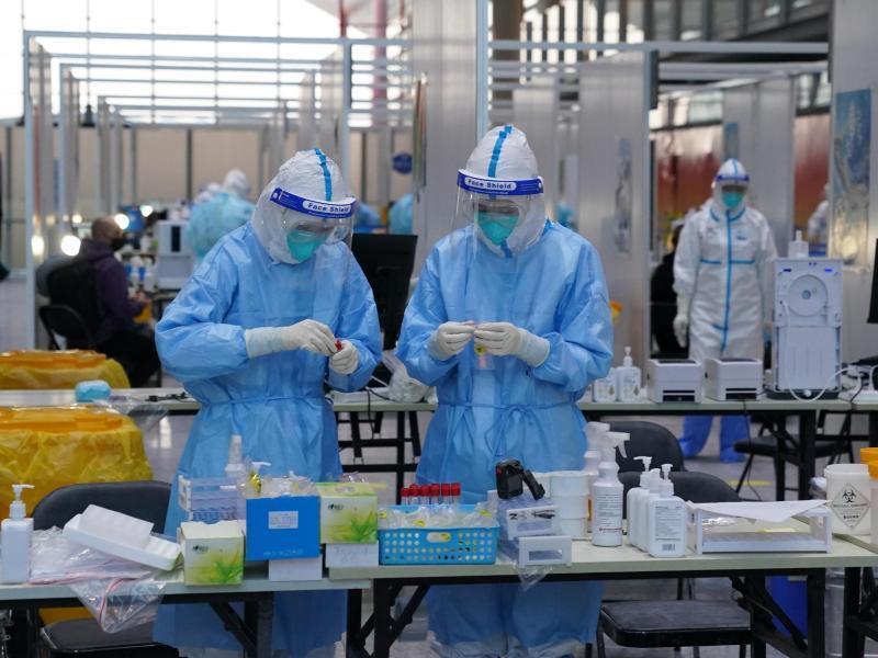 PCR-Prüfer in Schutzanzügen arbeiten in einem Prüfzentrum auf dem Flughafen von Peking. Foto: Andrew Milligan/PA Wire/dpa