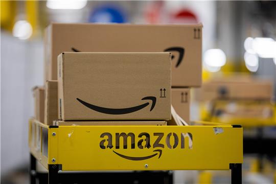 Pakete liegen in einem Logistikzentrum des Versandhändlers Amazon auf einem Wagen. Foto: Rolf Vennenbernd/dpa