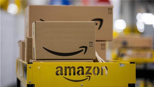 Pakete liegen in einem Logistikzentrum des Versandhändlers Amazon auf einem Wagen.