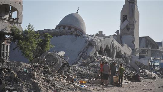 Hamas unter Druck - Will wohl künftig in Gaza mitregieren Palästinenser gehen zwischen den Ruinen von Gaza entlang.