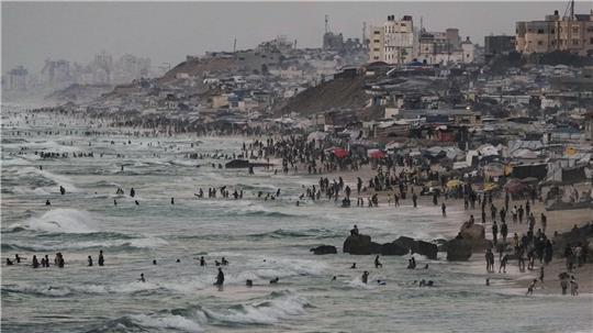 Palästinenser schwimmen in der Abenddämmerung im Mittelmeer in der Nähe eines Zeltlagers am Meer in Deir al-Balah im zentralen Gazastreifen. 