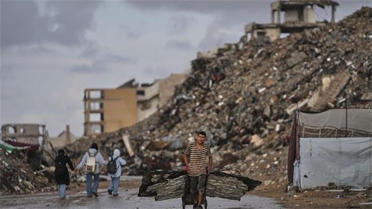 Palästinenser trägt Bleche durch Kriegsschutt in Gaza