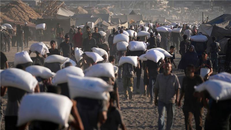 Bilder des Tages Palästinenser tragen Mehlsäcke, die von einem humanitären Hilfskonvoi auf dem Weg vom nördlichen Gazastreifen nach Gaza abgeladen wurden.
