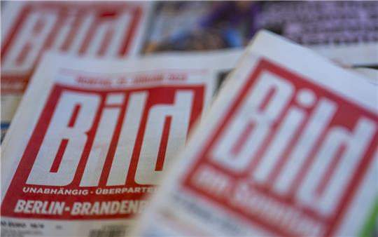 Papierausgaben der Zeitungen "Bild" und "Bild am Sonntag" liegen auf einem Tisch. Der Axel-Springer-Verlag will seinen Sparkurs bei der "Bild"-Zeitung mit schlankeren regionalen Strukturen voranbringen. Foto: Buchmann