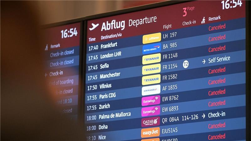 Passagiere blicken auf eine Anzeigetafel am Hauptstadtflughafen BER.