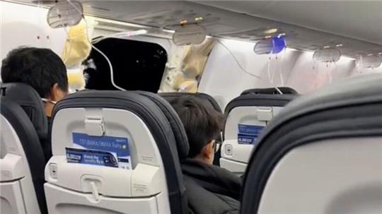 Passagiere, die in der Boeing 737-9 Max in der Nähe des abgerissenen Kabinenteils samt Fenster sitzen.