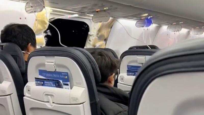 Passagiere sitzen in einer Boeing 737-9 Max in der Nähe des abgerissenen Kabinenteils.