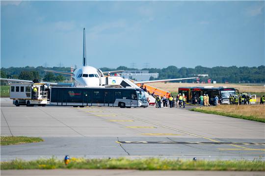 Passagiere verlassen nach der Notlandung in Hamburg das Flugzeug und steigen in bereitgestellte Busse. Foto: Walzberg/dpa