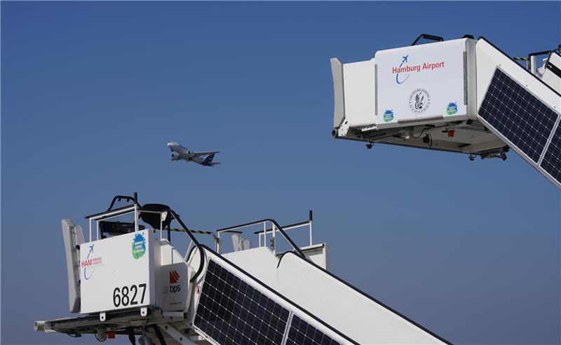 Passagiertreppen, an denen Solarpanel einer Photovoltaikanlage angebracht sind, stehen auf dem Flugvorfeld des Flughafens Hamburg Airport. Der Flughafen hat sich als erster deutscher Airport für CO2-neutral erklärt. Seit dem Jahr 2009 hat Hamburg Airport nach Angaben des Flughafens seine jährlichen CO2-Emissionen um knapp 80 Prozent - von 40 000 Tonnen auf 8700 Tonnen - reduziert. Foto: Marcus Brandt/dpa