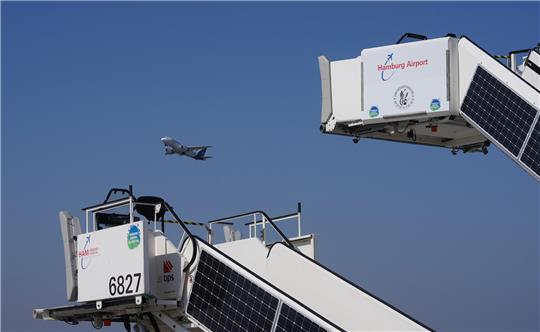 Passagiertreppen, an denen Solarpanel einer Photovoltaikanlage angebracht sind, stehen auf dem Flugvorfeld des Flughafens Hamburg Airport. Der Flughafen hat sich als erster deutscher Airport für CO2-neutral erklärt. Seit dem Jahr 2009 hat Hamburg Airport nach Angaben des Flughafens seine jährlichen CO2-Emissionen um knapp 80 Prozent - von 40 000 Tonnen auf 8700 Tonnen - reduziert. Foto: Marcus Brandt/dpa