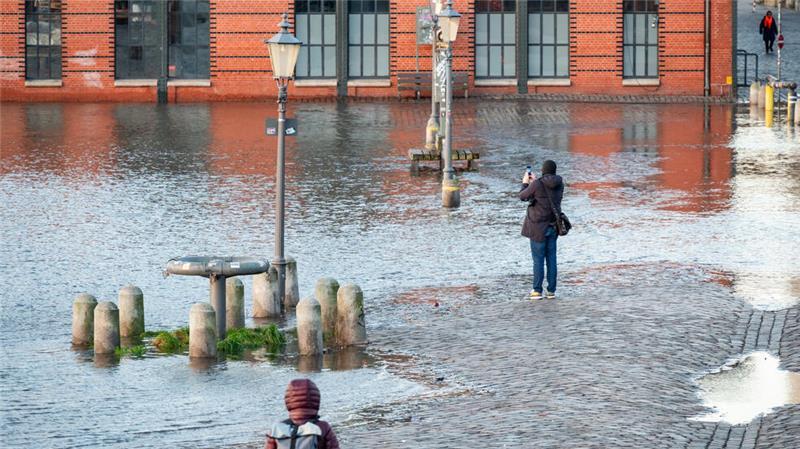 Passanten beobachten die erste Sturmflut des Jahres auf dem Hamburger Fischmarkt.