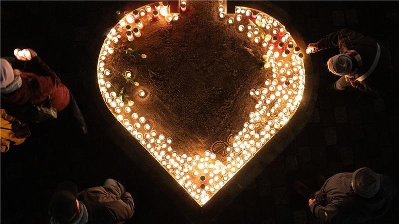 Passanten entzünden auf dem Neumarkt Kerzen am 81. Jahrestag der Zerstörung Dresdens.