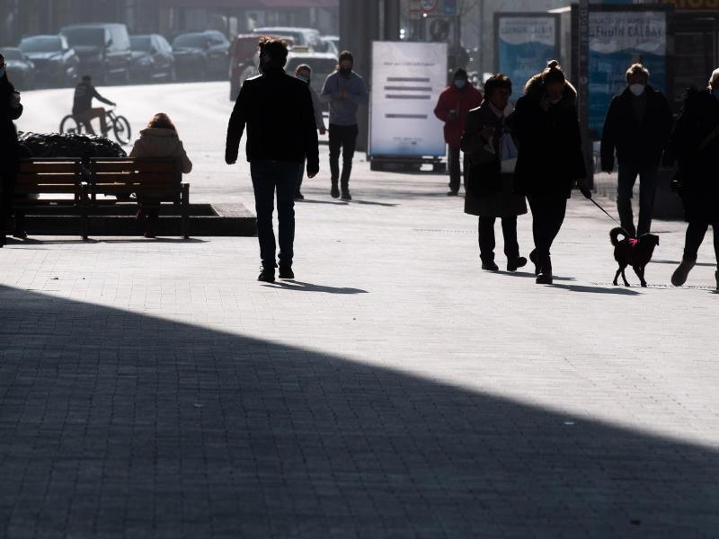 Passanten gehen bei Sonne durch die Innenstadt. Foto: Julian Stratenschulte/dpa