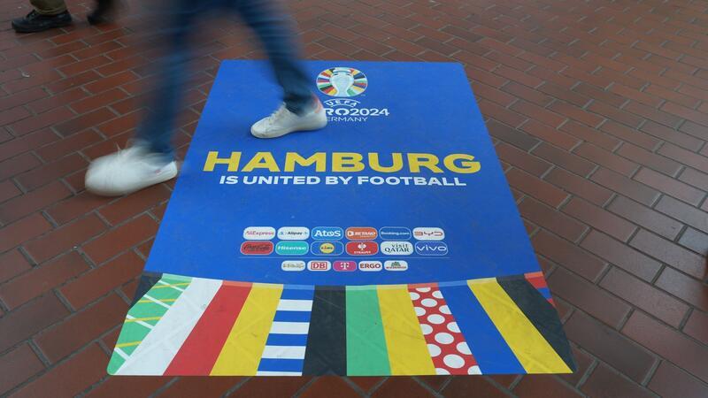 Passanten gehen über einen Euro 2024-Aufkleber in der Wandelhalle im Hamburger Hauptbahnhof.
