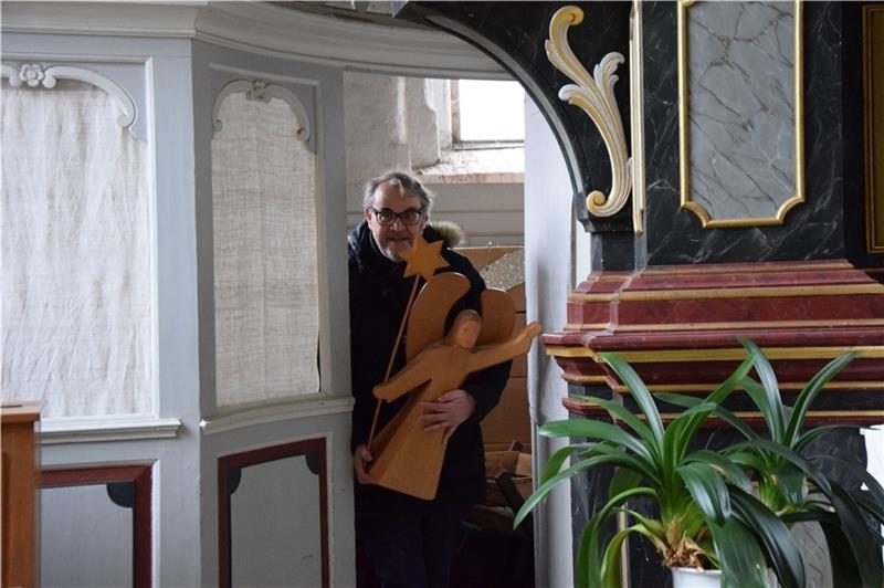 Pastor Olaf Prigge holt einen großen, hölzernen Engel aus der Sakristei der Kirche in Steinkirchen. Foto: Battmer