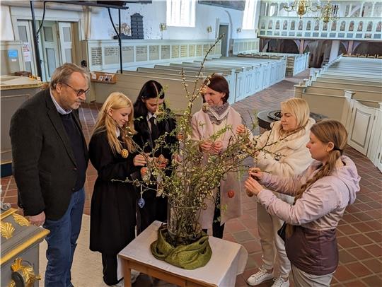Pastor Olaf Prigge schmückt mit den Ukrainerinnen Neonila Kutsepalo, Anastesia Kutsepalo, Nelly Holst (Übersetzerin), Iryna Schübkowa und Maria Kutsepalo (von links) in der Kirche den Osterstrauß.