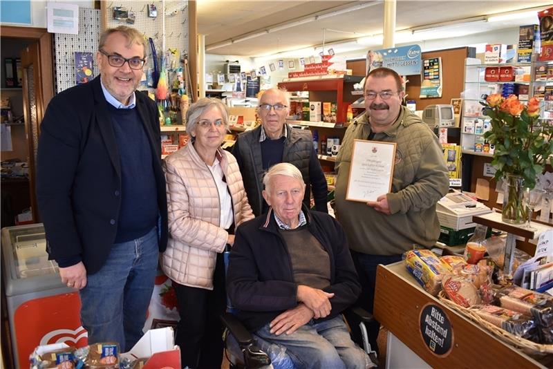 Pastor Olaf Prigge und die langjährigen Kunden Karin Lühders und Hinrich Stechmann überraschten Heinrich „Heino“ Somfleth (hinten) mit dem Bürgermeister Joachim Streckwaldt und nahmen ihn zum Jubiläum in die Mitte; der Kaufmannsladen in Mit