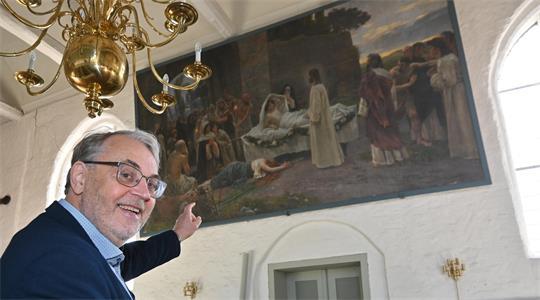 Pastor Olaf Prigge zeigt auf das Gemälde „Der Jüngling zu Naim“, geschaffen vom Künstler Rudolf Eichstaedt (1857–1924) in der Kirche in Mittelnkirchen.