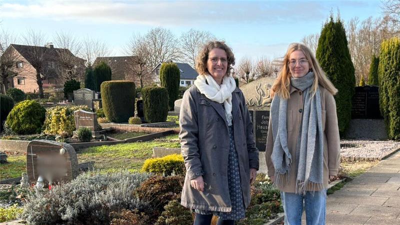 Pastorin Agnethe Krarup (links) und Vikarin Annika Kasten stehen am Übergang zwischen neuem und altem Friedhofsbereich.