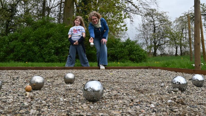 Pastorin Anika Röling übt mit ihrer Tochter Eva das Boule-Spiel im Pfarrgarten der St.-Nikolai-Kirche in Jork-Borstel vor der offiziellen Eröffnung am Sonnabend.