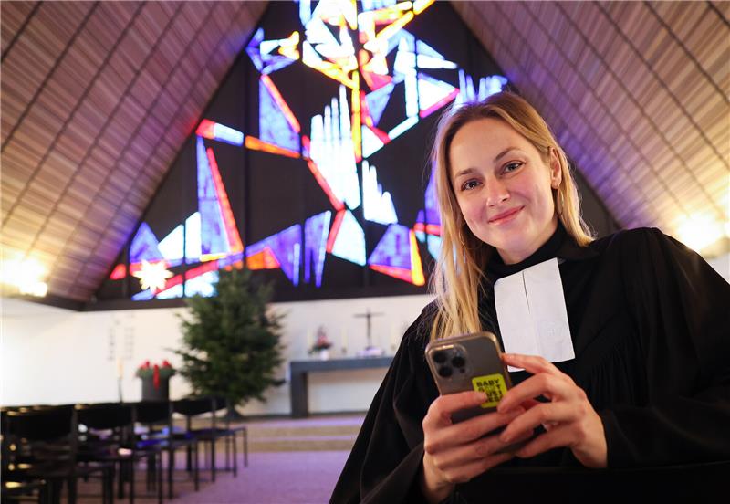 Pastorin Josephine Teske sitzt mit ihrem Smartphone in der Dietrich-Bonhoefer-Kirche der Gemeinde Meiendorf-Oldenfelde. Seit 2019 begeistert die Pastorin Menschen mit ihrem Instagram-Account „Seligkeitsdinge" für den Glauben. Foto: Christian Charisius/dpa
