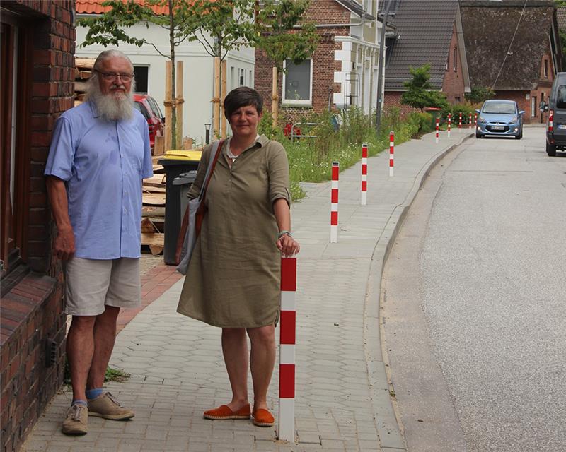 Peter G. Bartels und Sabine Heinemann zeigen die Sperrpfosten im sanierten Gehweg an der Hasselwerder Straße. Für Schulkinder und Mütter mit Kinderwagen ist stellenweise kein Durchkommen mehr. Foto: Michaelis
