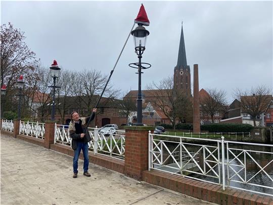 Peter Schmidt setzt den Laternen in der Buxtehuder Altstadt Weihnachtsmützen auf. Foto: Möller