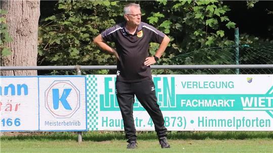 Peter Steffens steht an der Seitenlinie eines Fußballfeldes mit Armen in Hüften.