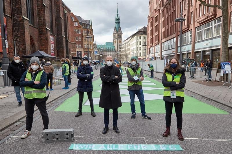 Peter Tschentscher (Mitte; SPD), Erster Bürgermeister von Hamburg, sowie Aktivisten von Fridays for Future stehen vor dem Schriftzug „WIR ALLE FÜR 1,5 GRAD“ in der Mönckebergstraße (Archivbild). Foto: Georg Wendt/dpa