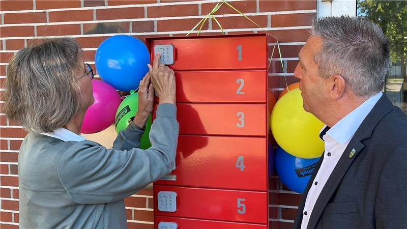Petra Abel von der Gemeindebücherei Steinkirchen-Grünendeich tippt den PIN-Code zum Öffnen des Abholfachs ein. Bürgermeister Timo Gerke schaut zu.