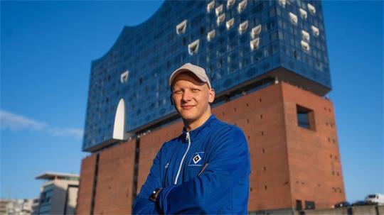 Petrit Merovci, frisch ernannter U18-Cheftrainer des HSV, strahlt vor der Elbphilharmonie in Hamburg – bereit für den nächsten großen Schritt Richtung Bundesliga.