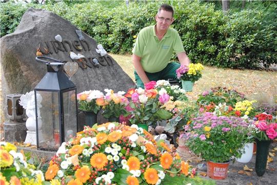 Pflegemaßnahme: Sven Bammann nimmt die verblühten Blumen am Stein des Urnengartens aus den Vasen und Töpfen und tauscht sie gegen blühende Blumen aus. Foto: Stief