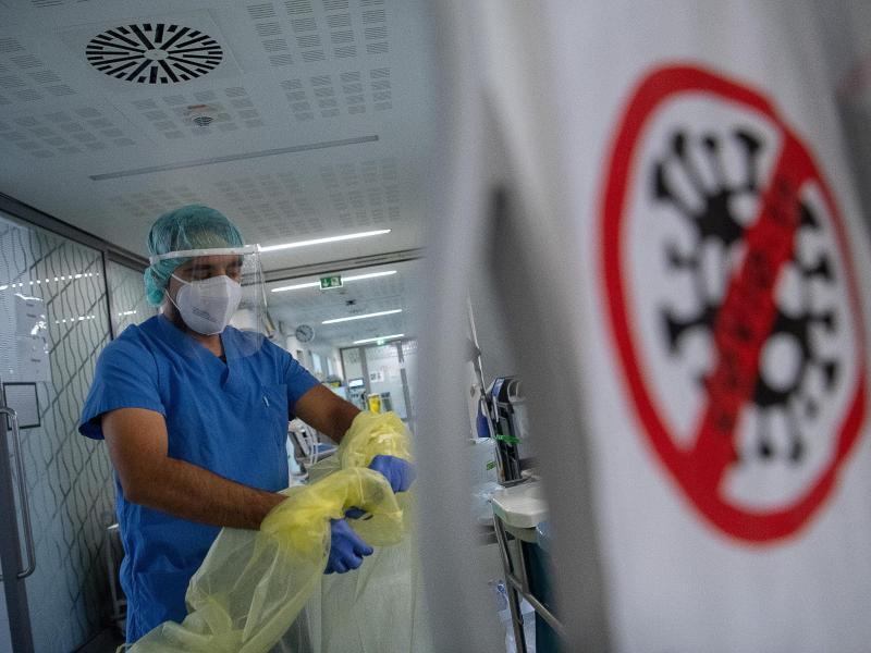 Pfleger zieht sich beim Verlassen der Intensivstation für Corona-Patienten seinen Schutzkittel aus. Foto: Sebastian Gollnow/dpa/Symbolbild