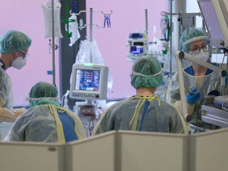 Pflegerinnen und Pfleger sowie eine Ärztin kümmern sich auf der Intensivstation um einen Patienten. Foto: Sebastian Gollnow/dpa
