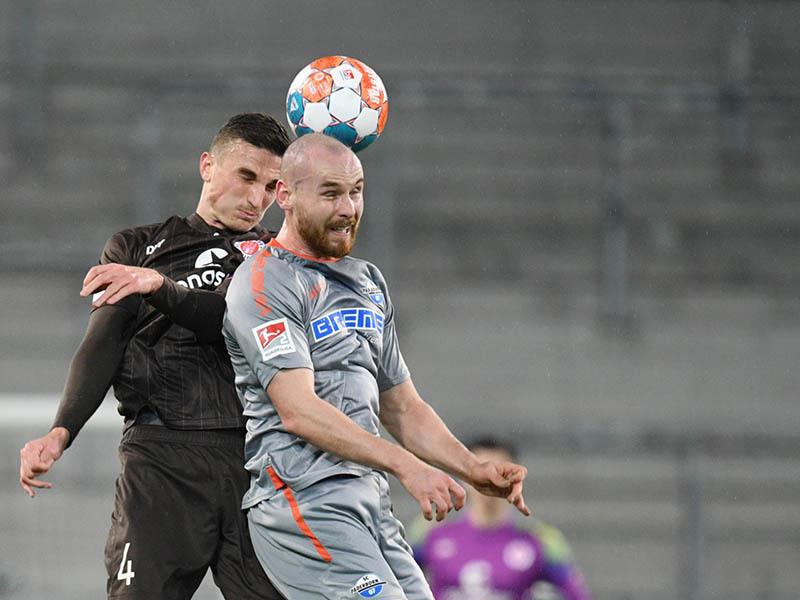 Philipp Ziereis (l) von St. Pauli und Jannis Heuer von Paderborn kämpfen um den Ball. Foto: Daniel Reinhardt/dpa