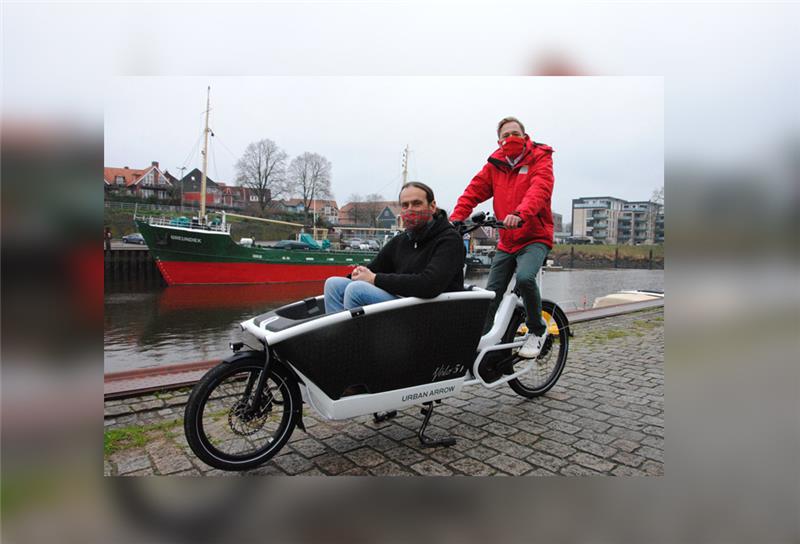 Platz für zwei Kinder, einen Erwachsenen oder den Einkauf: Christian Ückert vom Verein „Stade fährt Rad“ (vorn) und Tillmann Wilhelm, Überbringer der Spende der Postcode Lotterie, zeigen wie es geht.  Foto: Stief