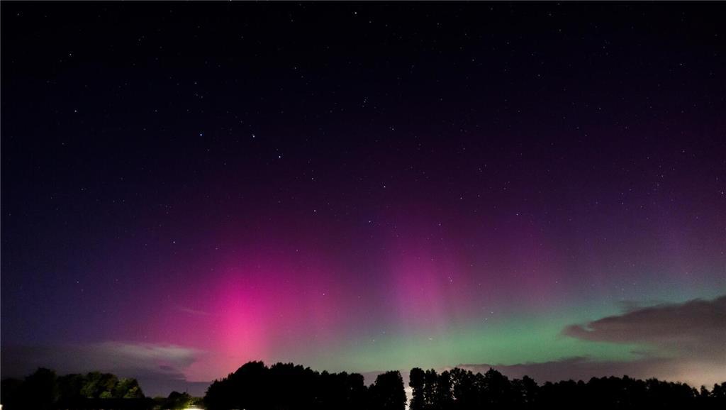 Polarlichter in Pink und Grün erhellen die Nacht.