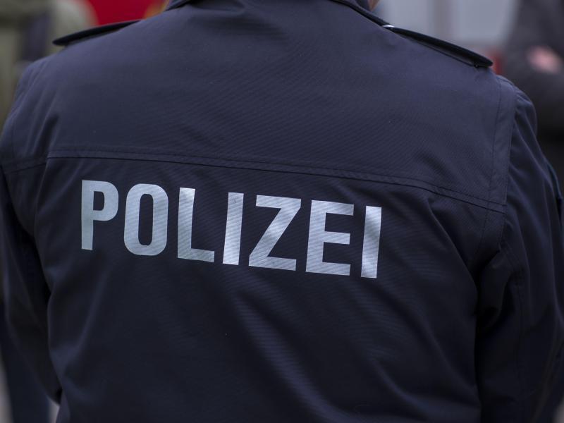 «Polizei» steht auf der Uniform eines Polizisten. Foto: Jens Büttner/zb/dpa/Symbolbild