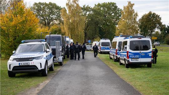 Polizeiautos stehen auf einer Wiese in Tauche. 