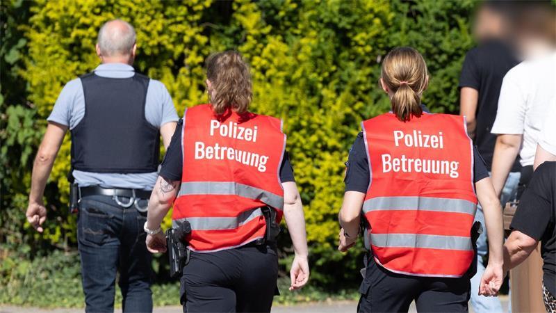 Polizeibeamte betreuen Angehörige vor einem Gebäude einer Jugendeinrichtung – dem Tatort.