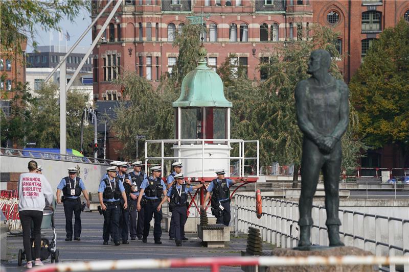 Polit-Prominenz, viel Wind und ein sexy Auftritt bei Einheitsfeier in Hamburg Polizeibeamte gehen an den Absperrungen am Maritimen Museum in der Hafencity entlang. Foto: Marcus Brandt/dpa