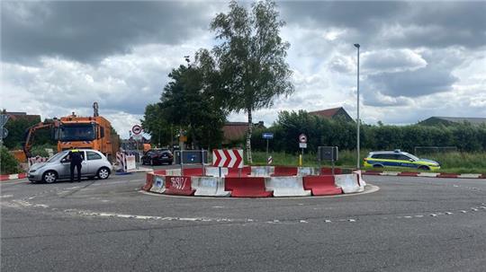 Polizeibeamte halten an der gesperrten Dammhauser Straße und am Kreisel Autofahrer an.