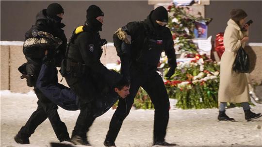 Polizeibeamte halten einen Mann fest, der Blumen zu Ehren von Alexej Nawalny an einem Denkmal für die Opfer der sowjetischen Unterdrückung in St. Petersburg, Russland, niedergelegt hat.