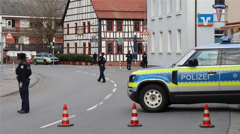 Täter hält Bankmitarbeiterin stundenlang fest - Motiv unklar Polizeibeamte sichern die Straße rund um die Bankfiliale.